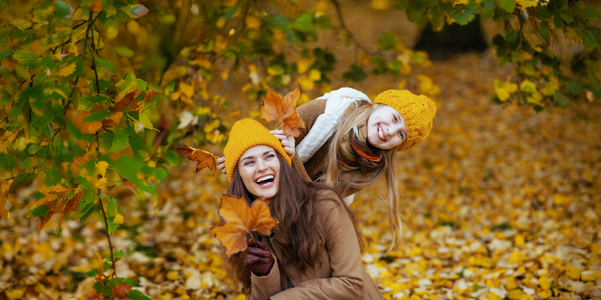 Fall into savings ad Compian photo featuring a mother and daughter playing outside in the leaves. 